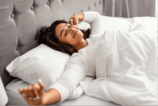 How a Grounding Sheet Works Explained: a woman peacefully waking up in bed feeling refreshed after a good night's sleep.